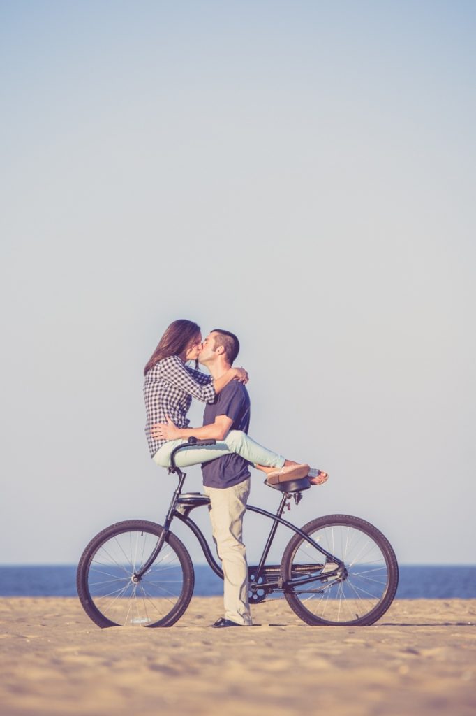 Engagement session couple kissing on a bike in Virginia Beach