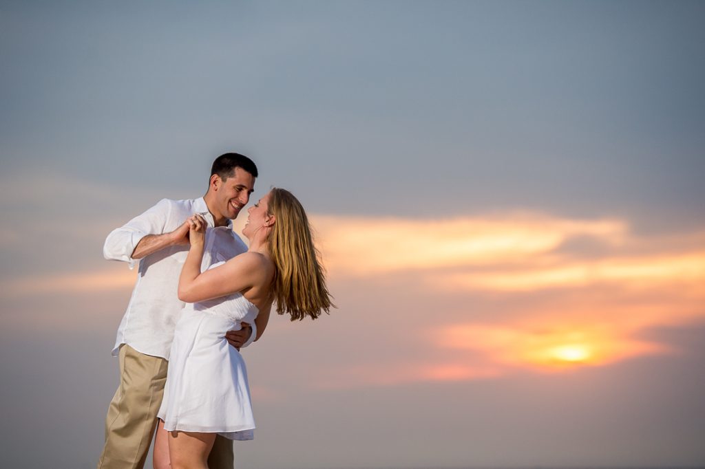 Engagement session couple holding hands on the beach at sunset