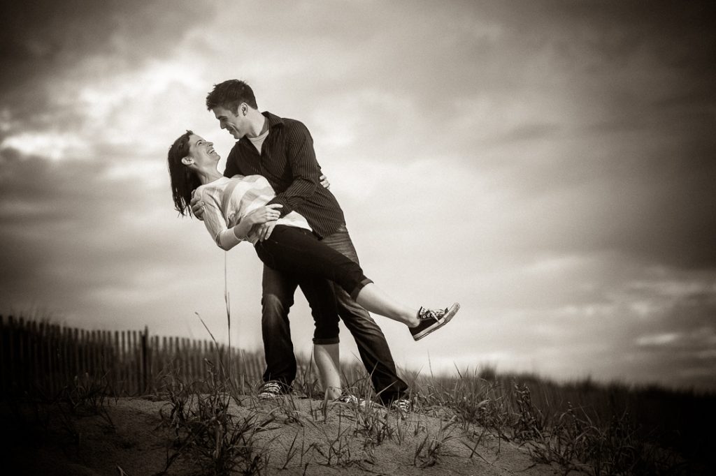 Engagement session couple black and white dipping on the beach at sunset