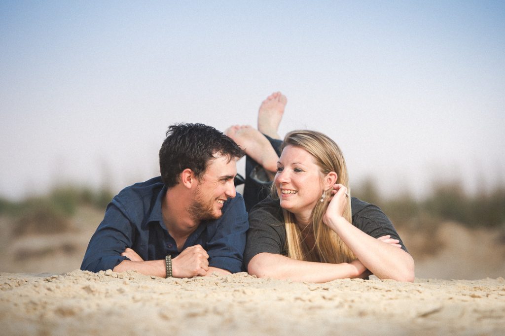 Engagement session couple laying on the sand
