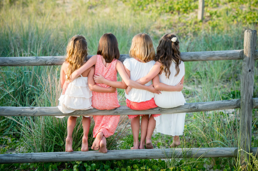 Family portrait of four cousins sitting on a railing