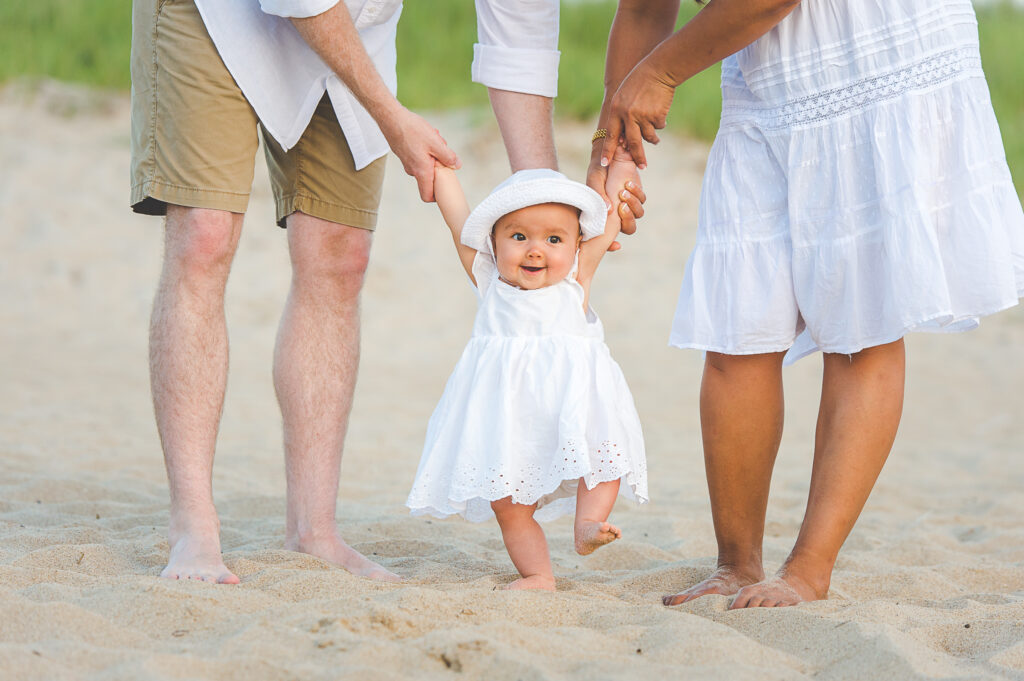 Cute baby in the family portrait walking on the sand