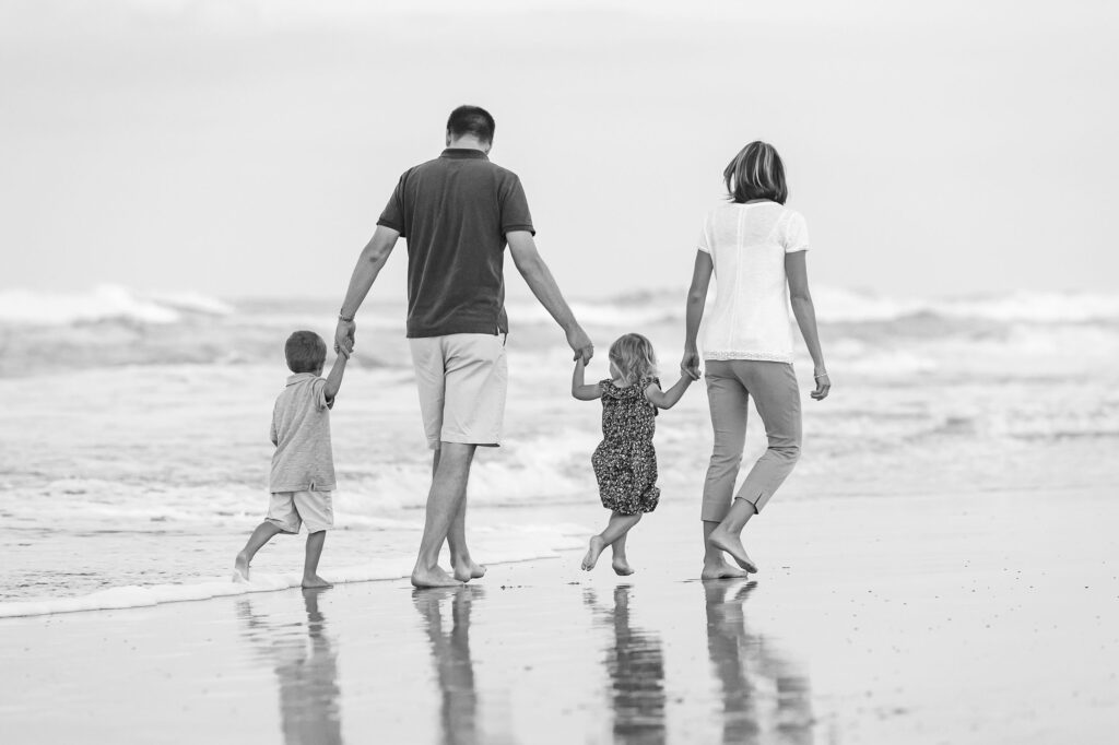 Black and white family portrait walking hand in hand on the beach