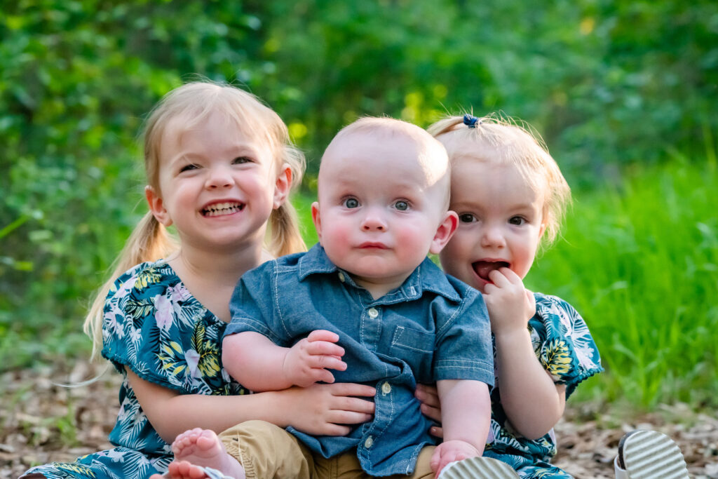 Three siblings smiling in their family portrait