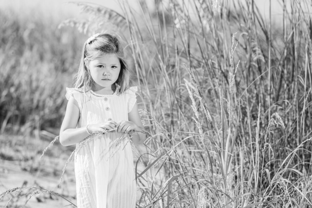 Black and white photo of a young girl on the beach in her family portrait