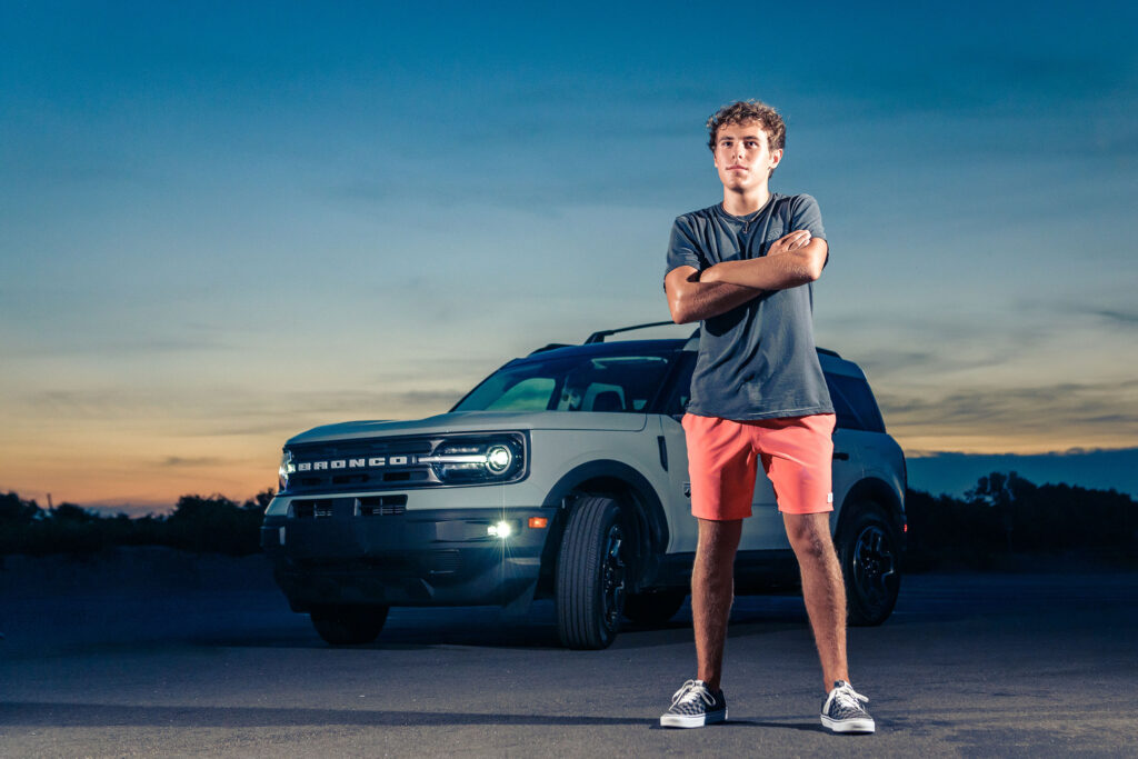 Young man at his senior portrait session with his new Ford Bronco at Little Island Park