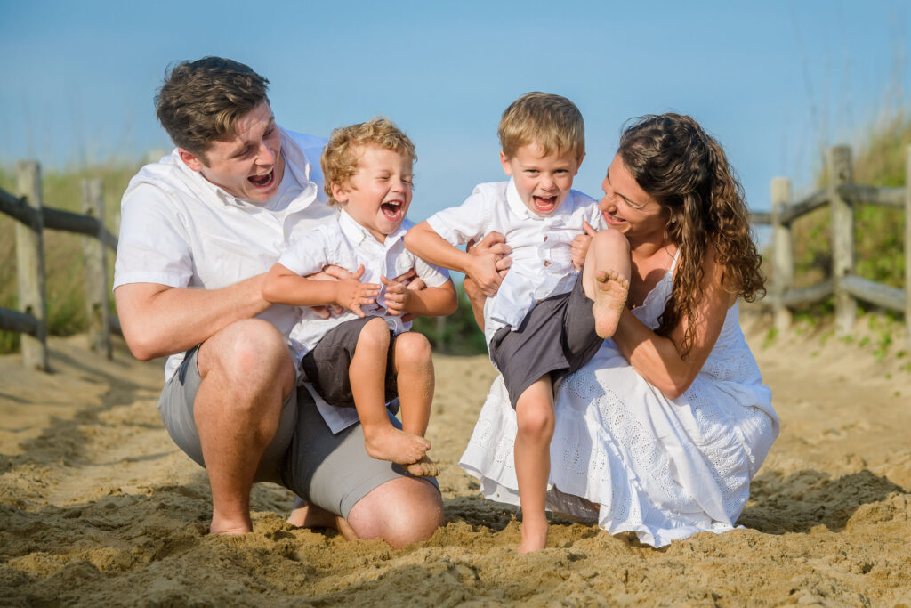 Candid moment of mom and dad tickling their sons at their family portrait session in Sandbridge