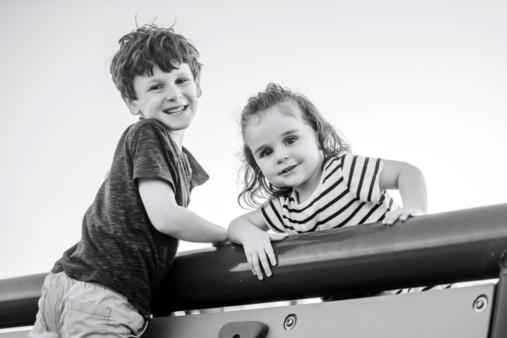 Black and white candid moment of siblings playing in the park
