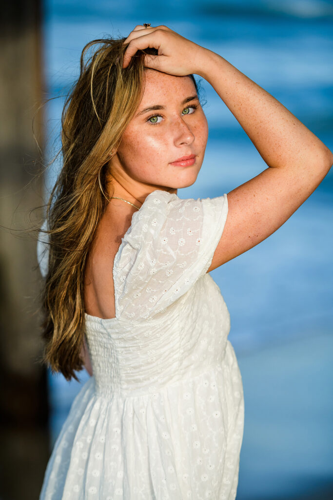 Pretty young girl at her senior portrait session in a modeling pose on the beach