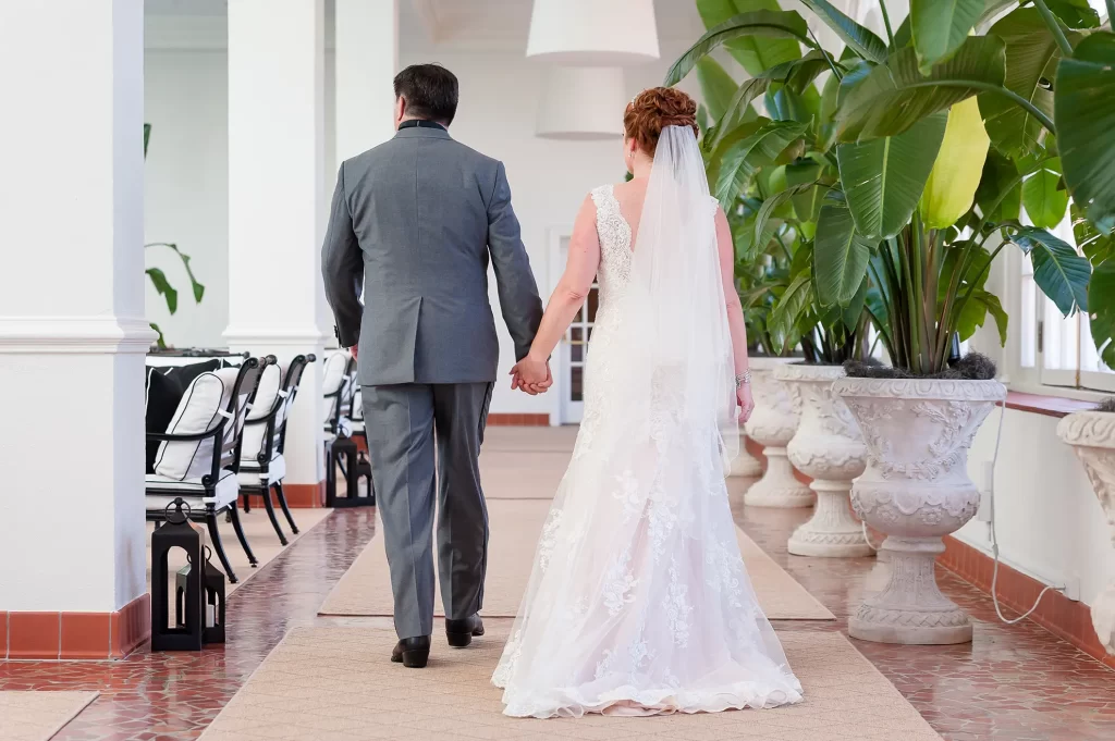 Bride and Groom walking through the Cavalier Hotel pool room