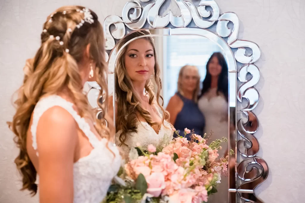 Bride looking into mirror with Grandmother and Mother in the reflection