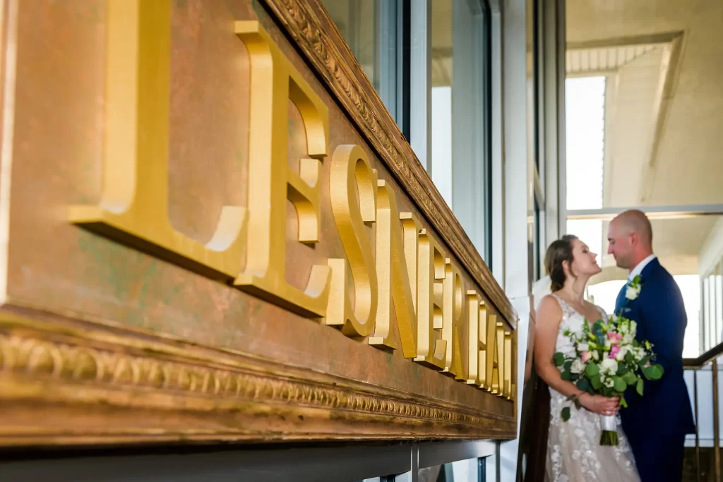 Bride and Groom next to the sign of the Lesner Inn Hall